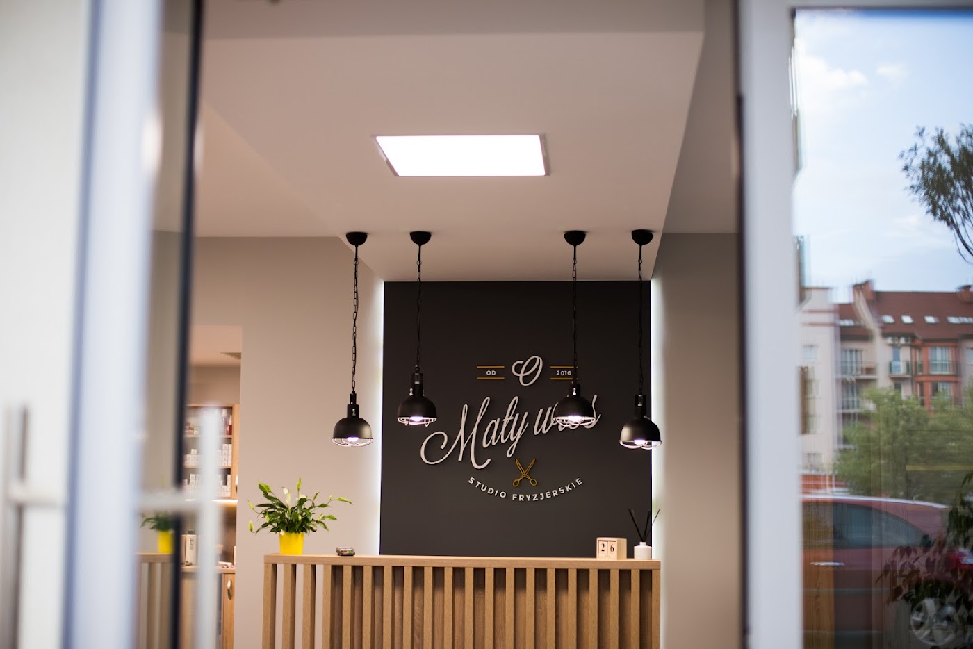 Recepcja studia z ciemną ścianą z logo i wiszącymi lampami